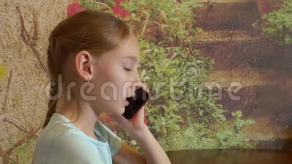 可爱的少女在室内使用智能手机聊天视频的预览图