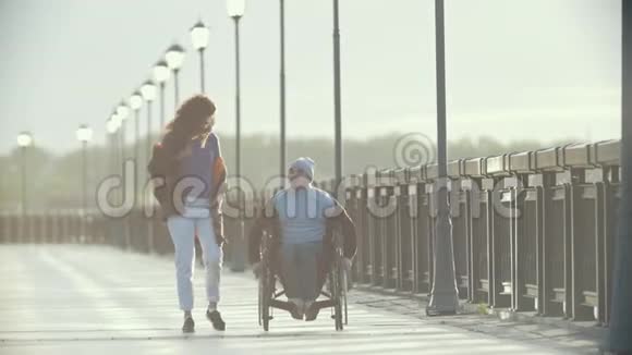 坐轮椅的残疾人和女朋友一起在码头上散步视频的预览图