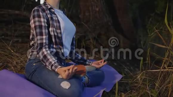 少女坐在瑜伽垫上在森林里冥想视频的预览图
