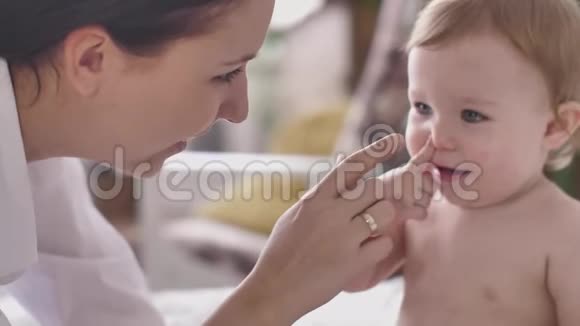 爱的母亲亲吻抚摸可爱的顽皮的小男孩笑着享受养育孩子在家视频的预览图