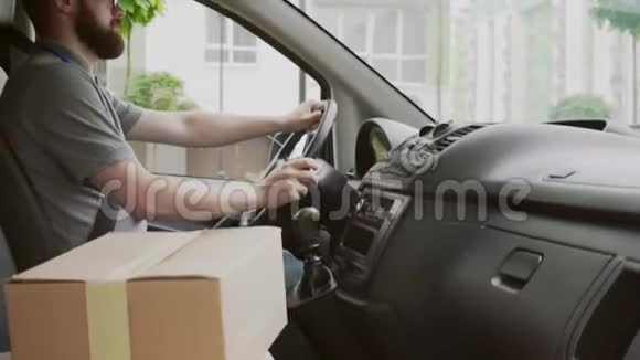 带纸盒的年轻快递员驾驶车的侧视图视频的预览图