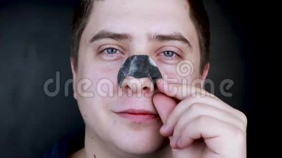 一个男人穿上并从黑点上取下一条鼻子的带子从黑头和喜剧片上清理煤炭的概念视频的预览图