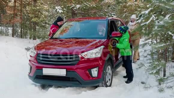 一家人推着红车在冬天的森林里陷在雪里越野车卡在雪道上穿过冬天的林地家庭视频的预览图