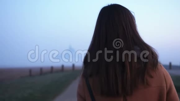 电影院后景美丽的年轻旅游妇女步行到日出雾蒙圣米歇尔要塞慢运动视频的预览图