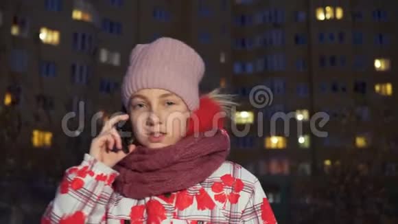 晚上打手机的少女走在冬天的大街上少女在冬季街头谈论智能手机视频的预览图