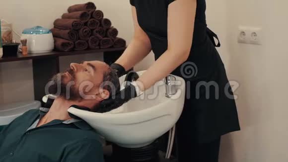 发型师在理发店用洗发水洗头理发师在剪前洗手男头男性头发护理视频的预览图