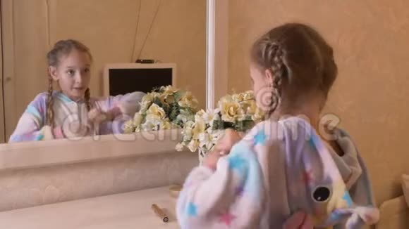 年轻女孩在白色卧室里做嘴唇化妆前镜穿着睡衣的小女孩独角兽用液体口红视频的预览图