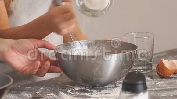 家庭合作愉快穿围裙的小女孩在碗里洒面粉做面团视频的预览图