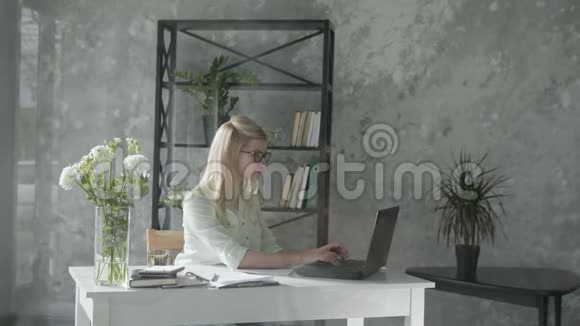 快乐的成年女孩为电脑工作为成功完成的工作感到高兴同时把双手抛在脑后视频的预览图