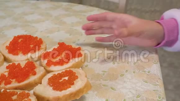 用红色鱼子酱合上女性手拿三明治脸少女咬面包三明治加红色鱼子酱视频的预览图