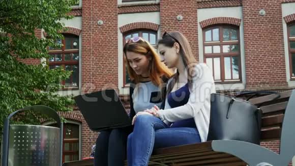 现代女性学生在校园里坐在长凳上一起在学生项目上的笔记本电脑上工作视频的预览图