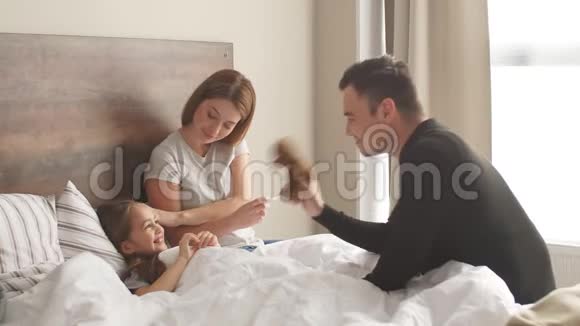 充满欢乐的爸爸妈妈和生病的女儿躺在床上视频的预览图