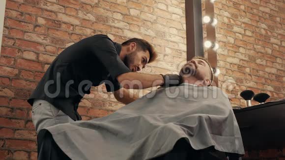 低角度拍摄聚焦理发师剪胡子给客户视频的预览图