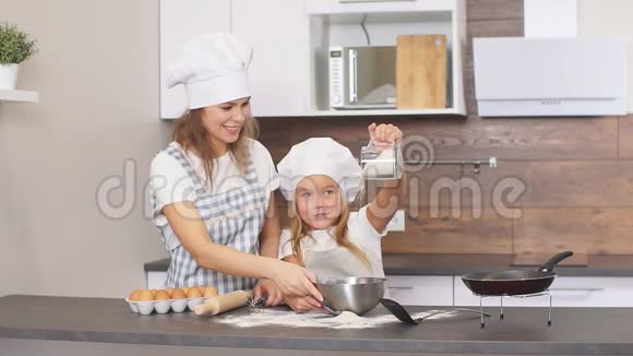 小女孩在烤蛋糕前用杯子洒面粉视频的预览图