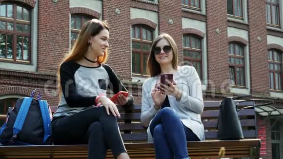 现代女生上课前使用手机坐在校园公园的长椅上大学概念视频的预览图