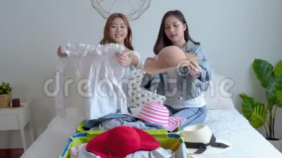 鹤镜头放大视频的两个美丽的亚洲妇女正在选择衣服在一个手提箱为旅行做准备t的概念视频的预览图