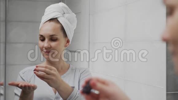 成人头上有毛巾女士涂洗剂或油照镜子视频的预览图