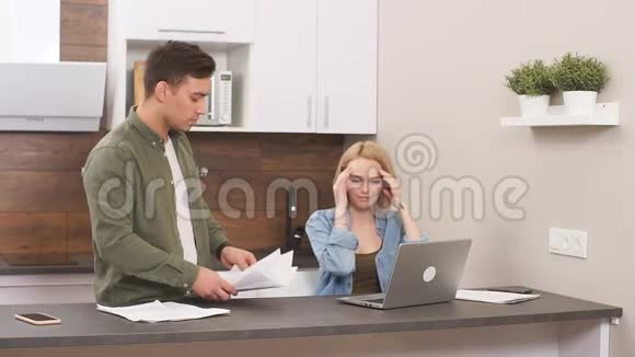 令人困惑的是一家人坐在家里研究家庭商业文件用现代笔记本电脑工作视频的预览图