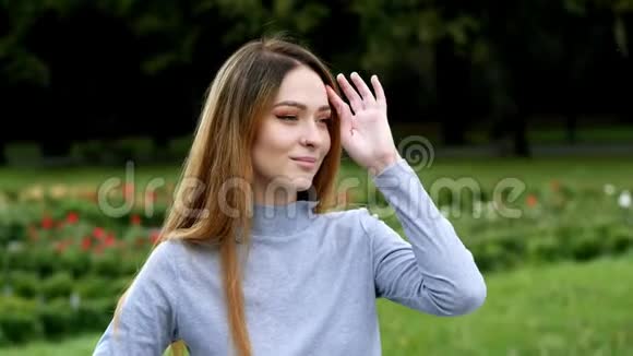 一幅迷人微笑的现代红头发女人戴上眼镜在公园里看着相机的特写照片视频的预览图