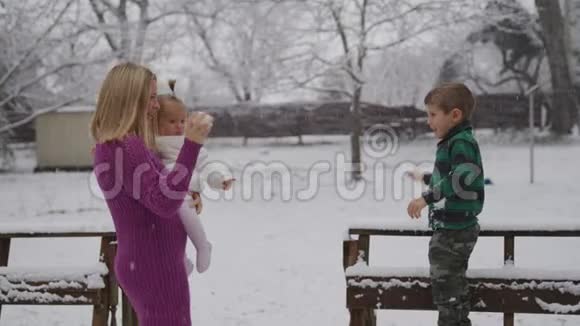 年轻的金发女人带着她的孩子在雪地公园享受视频的预览图
