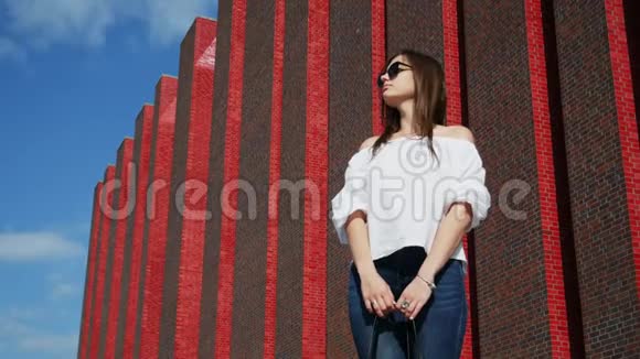 美丽的女人站在城市街道上靠近一座现代化的砖楼展览中心视频的预览图