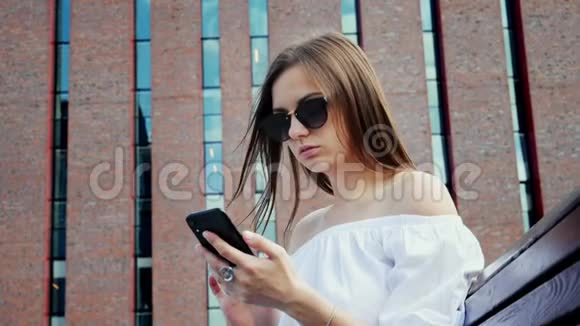 现代年轻女子在街上使用手机现代砖楼视频的预览图