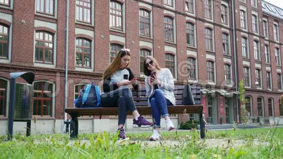 现代女生上课前使用手机坐在校园公园的长椅上大学概念视频的预览图