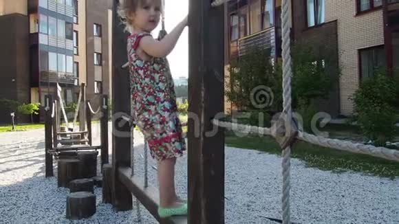 一个小女孩走在操场上的绳梯和绳桥上慢动作视频的预览图