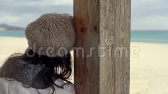 冬天一个暴风雨般的天空在海边的一个封闭的酒吧的日光室里年轻的女人倚在一根木杆上看着视频的预览图