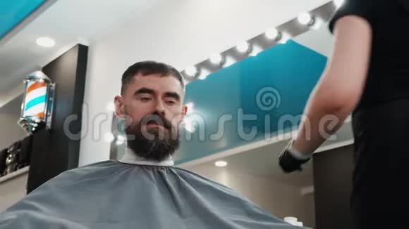 理发师在理发店给严肃的男人梳头和理发视频的预览图