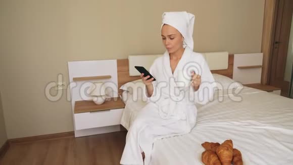 女孩用电话在床上喝咖啡视频的预览图