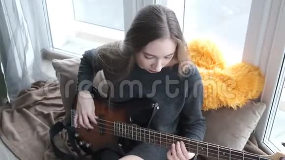窗前弹吉他的年轻漂亮女孩视频的预览图