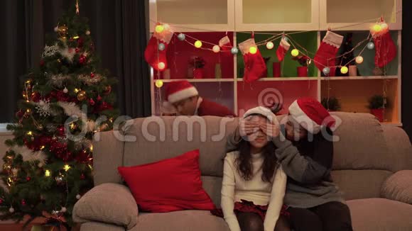 圣诞节父母们闭上眼睛送上一个礼物盒给女儿一个惊喜幸福的家庭视频的预览图