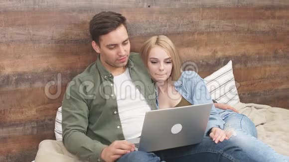 迷人的年轻夫妇在床上放松在笔记本电脑上观看一段有趣的视频视频的预览图