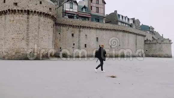 宽镜头快乐兴奋的游客与背包走近史诗山圣米歇尔城堡诺曼底慢动作视频的预览图