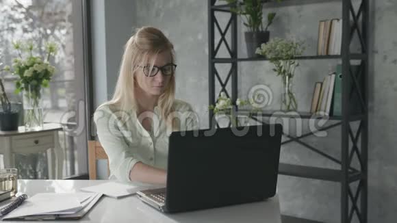 年轻女商人的肖像小企业主在办公室里用笔记本电脑工作看数字显示器和视频的预览图