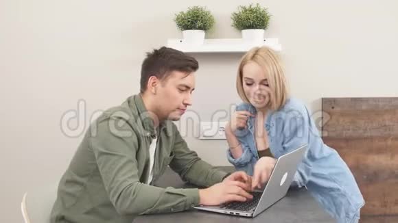 有趣的新婚夫妇在厨房里玩笔记本电脑买了度假票视频的预览图