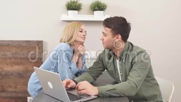 快乐的年轻一家正在计划一次联合度假新婚夫妇在厨房用笔记本电脑买票视频的预览图
