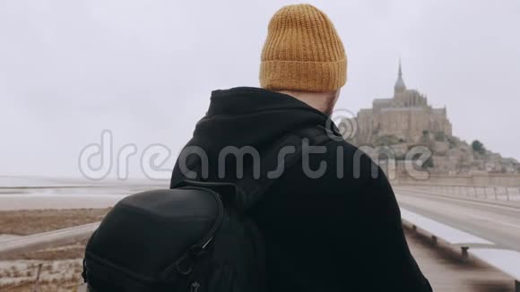 后景快乐兴奋的游客男子拍摄智能手机视频史诗山圣米歇尔城堡在诺曼底慢动作视频的预览图