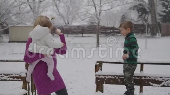 年轻的金发女人带着她的孩子在雪地公园享受视频的预览图