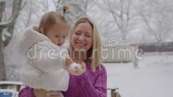 年轻的金发女郎带着可爱的女婴在雪地公园里玩视频的预览图