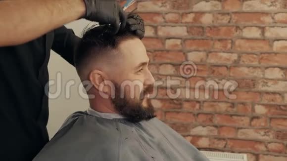 面对年轻人在理发店的轮廓视图中用剪刀和梳子理发理发师剪雄性头发视频的预览图