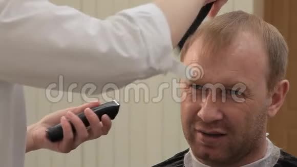 一个女人Barber用电动修剪器和梳子剪男人的头发开始剪眉毛视频的预览图