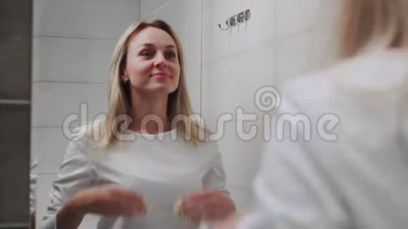 浴室里镜子前的白人女人洗脸护肤健康视频的预览图