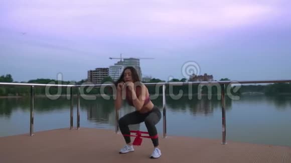 健身妇女在湖边码头蹲视频的预览图