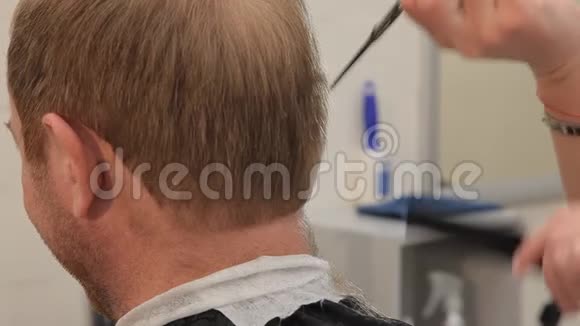 理发师用剪刀和梳子把一个人的头发从后面剪下来巴伯大师的领导视频的预览图