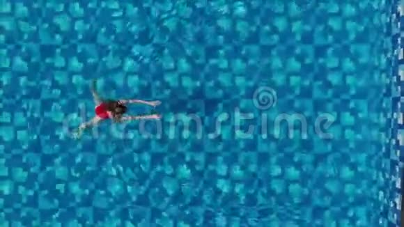 穿红色泳衣的女人正上方在一个清澈的蓝色水池里游泳高空俯视图视频的预览图
