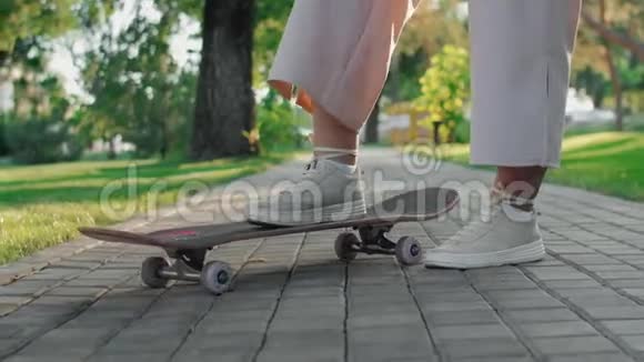 一个穿着米色运动鞋的女人的漂亮腿站在滑板上视频的预览图