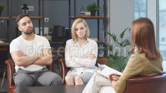 年轻的白种人夫妇互相冒犯坐在咨询家庭心理学家视频的预览图