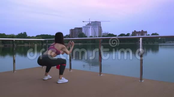 健身妇女在湖边码头蹲视频的预览图